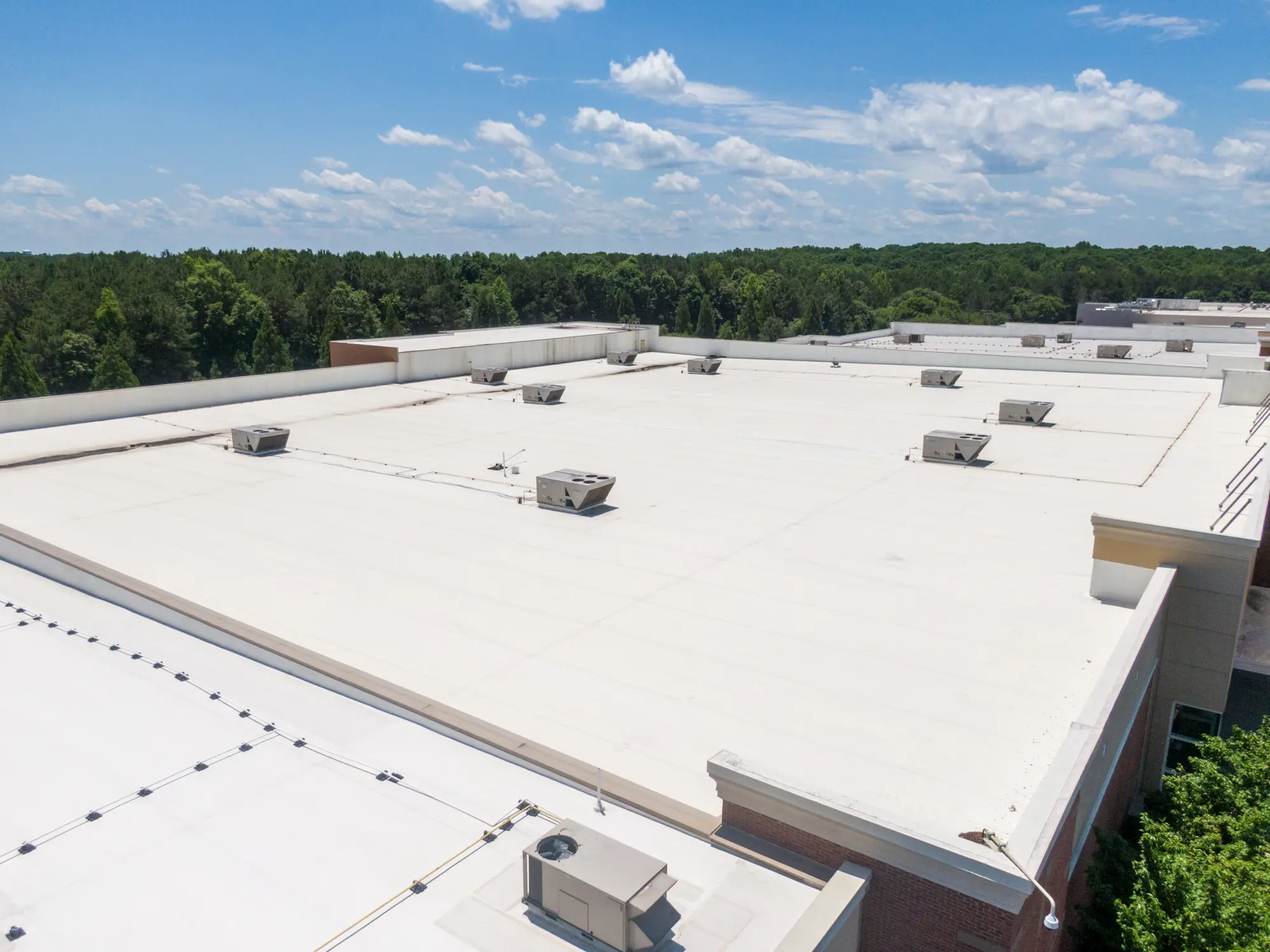 White membrane roof on a large commercial building with multiple rooftop HVAC units.